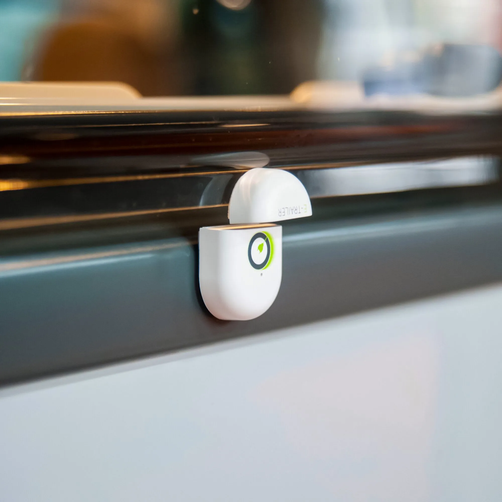 Weißer E-Switch Tür- und Fenstersensor mit zweiteiligem Gehäuse an einem dunklen Fensterrahmen