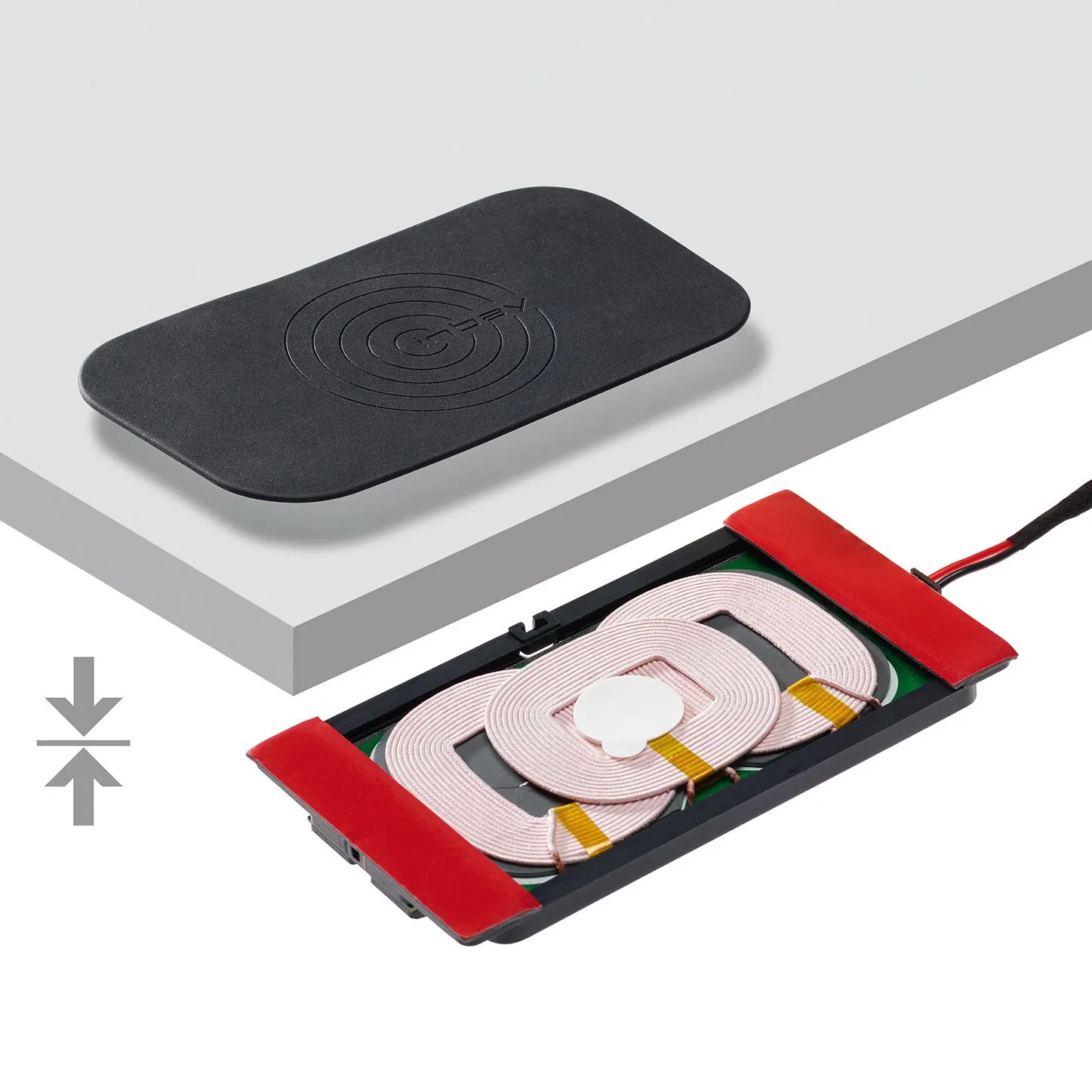 Schwarzes Wireless-Charger-Pad mit eingeprägtem Ladesymbol und geöffnete Ladeeinheit mit drei sichtbaren Spulen und Anschlusskabel