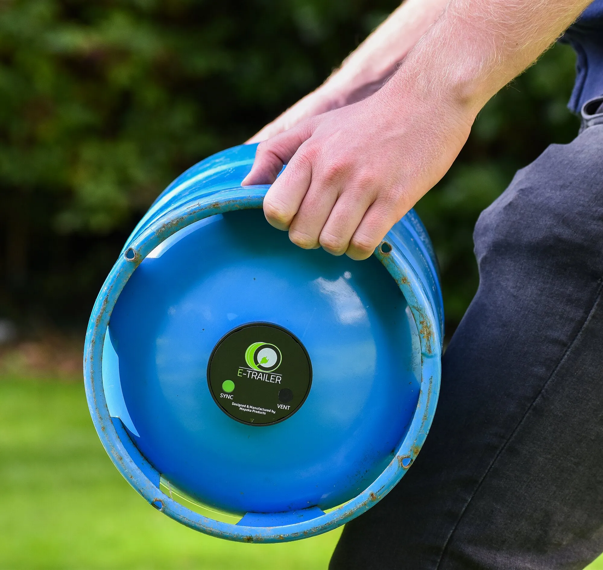 Person hält eine blaue Gasflasche mit montierter E-Gaslevel-Füllstandsanzeige und grün leuchtender SYNC-Anzeige 马会