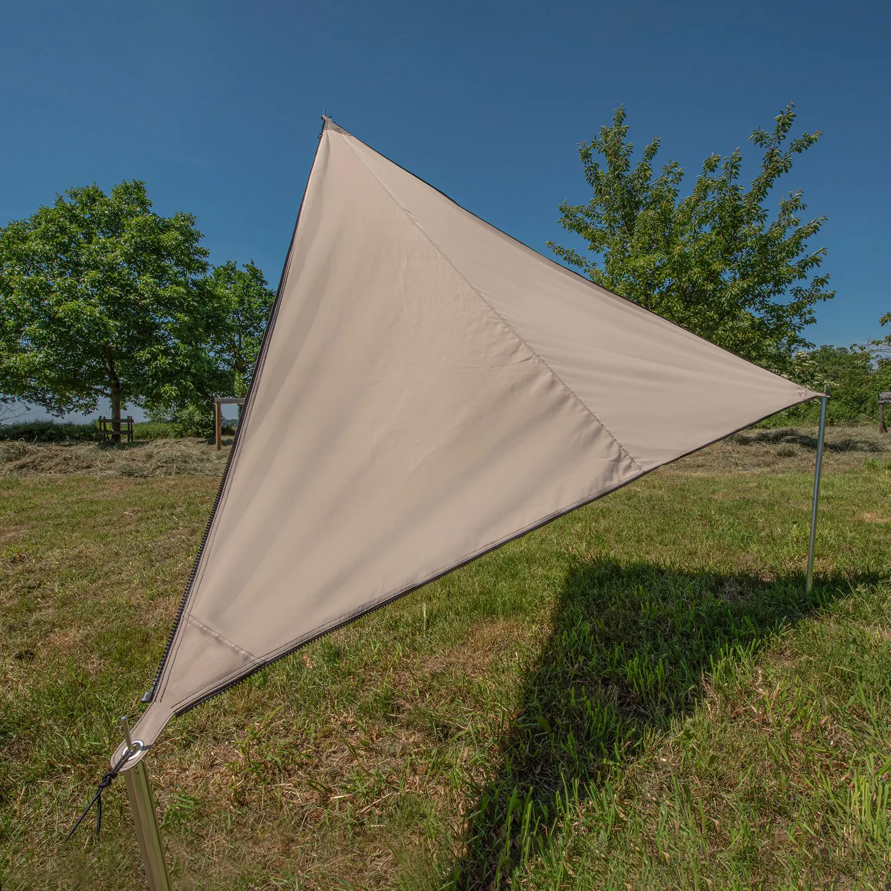 Beiges TC-Zip Canvas Africa Nomad-Sonnensegel in Dreiecksform, an Pfosten gespannt, mit Reißverschlusskante, im Garten