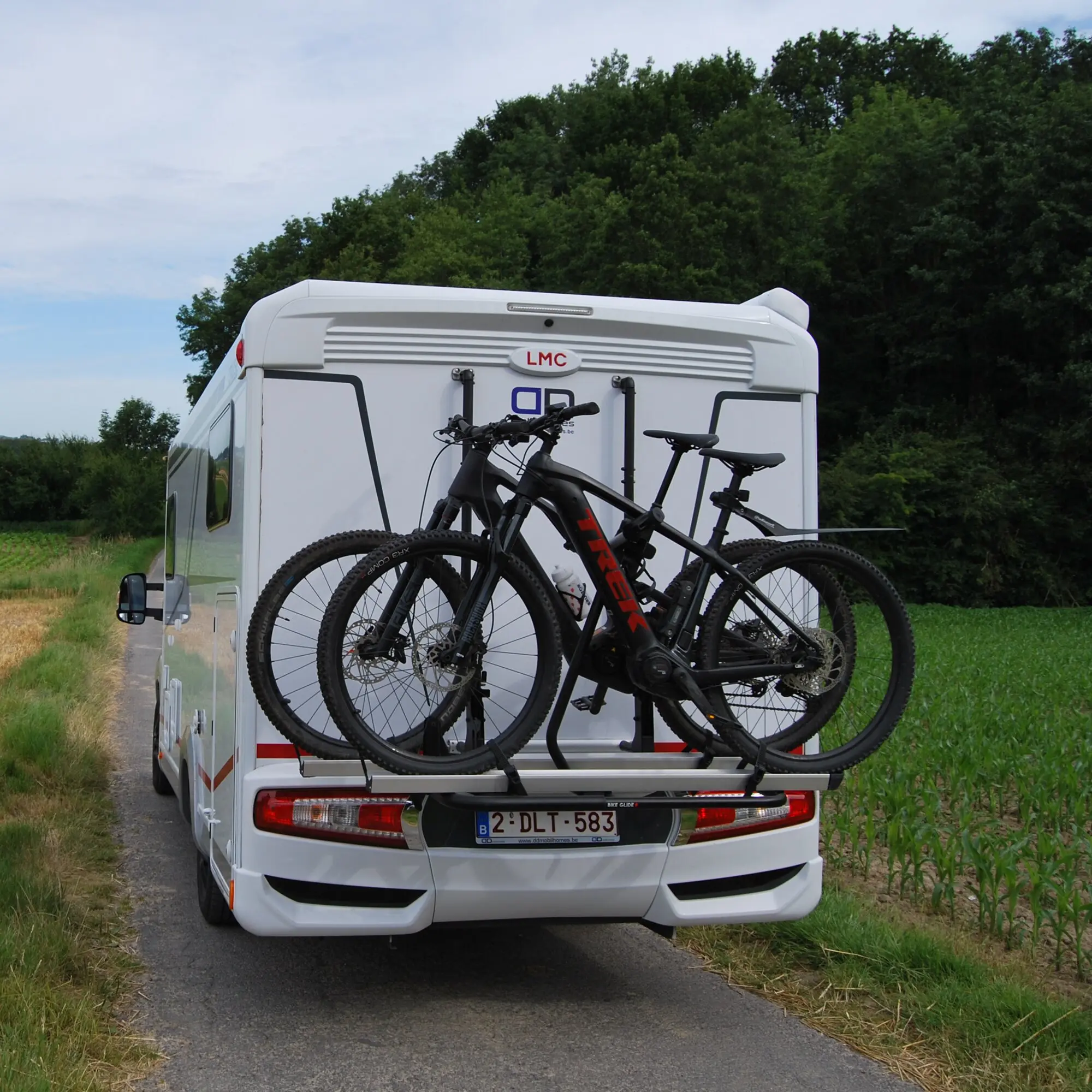 Zwei Mountainbikes in schwarzer Lackierung mit rotem Akzent sind auf einem hinteren Fahrradträger eines weißen Wohnmobils befestigt