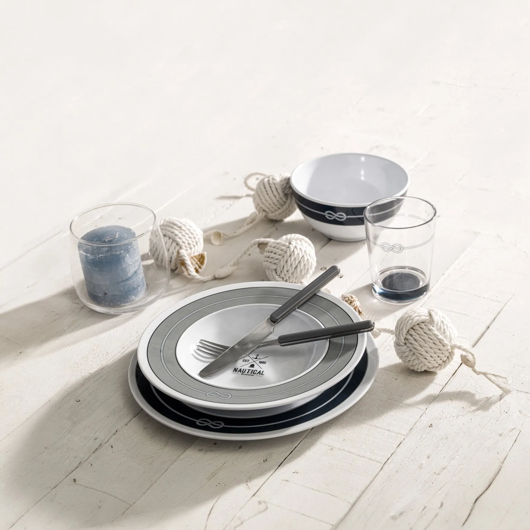16-teiliges Geschirrset Nautical mit weißen Tellern, grauem und dunkelblauem Tauwerkdekor, Schalen und Besteck auf Holztisch
