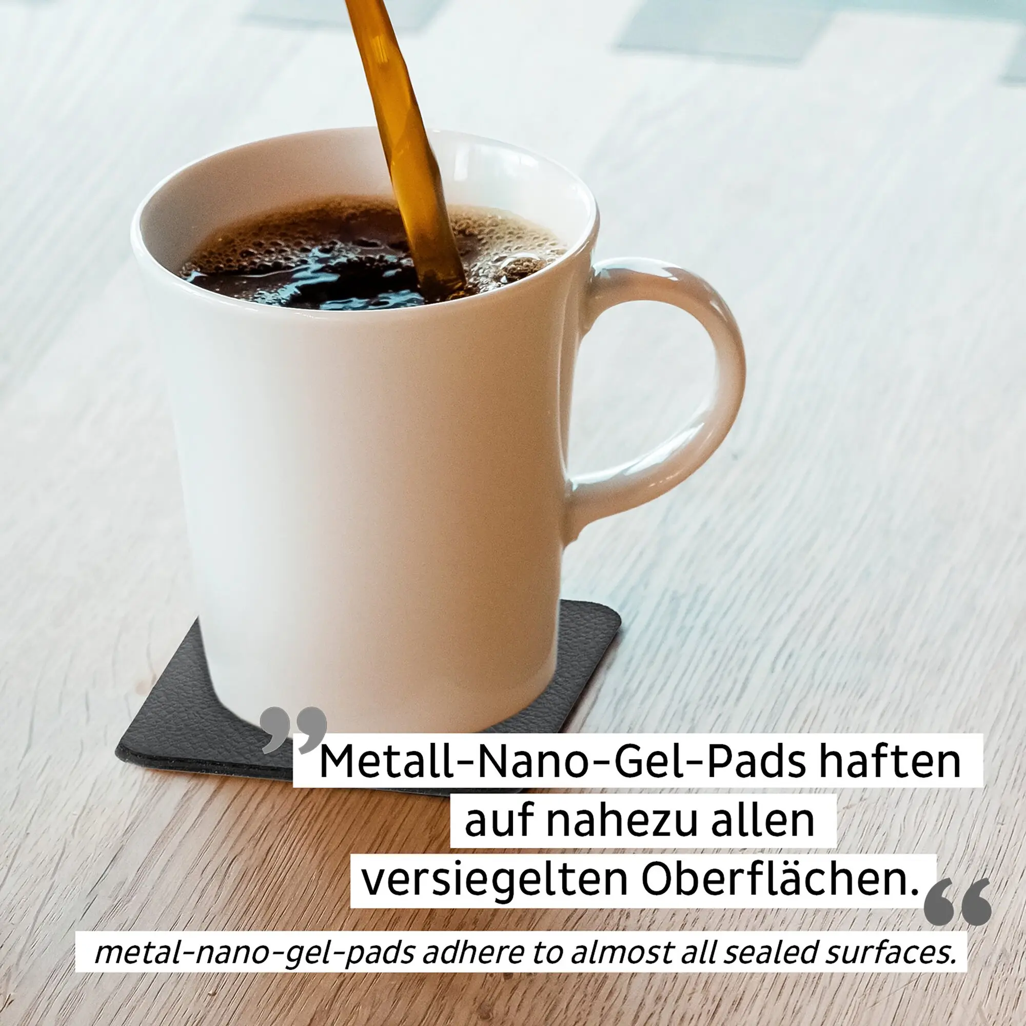 Weiße Magnet-Porzellantasse Camping auf einer schwarzen Unterlage; aus der Tasse fließt dunkler Kaffee, Hintergrund ist heller Holztisch